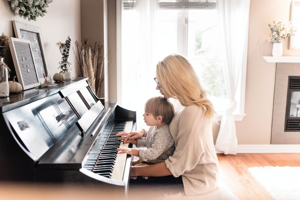 A music teacher teaching a kid how to play a piano