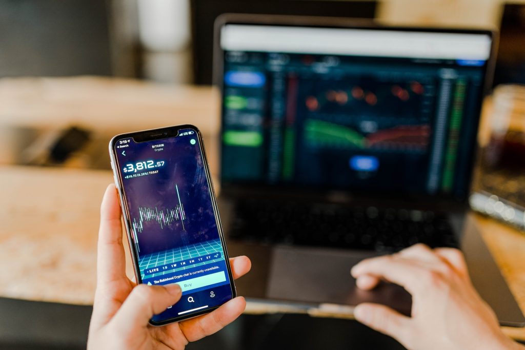 A person using finance apps on a phone and laptop